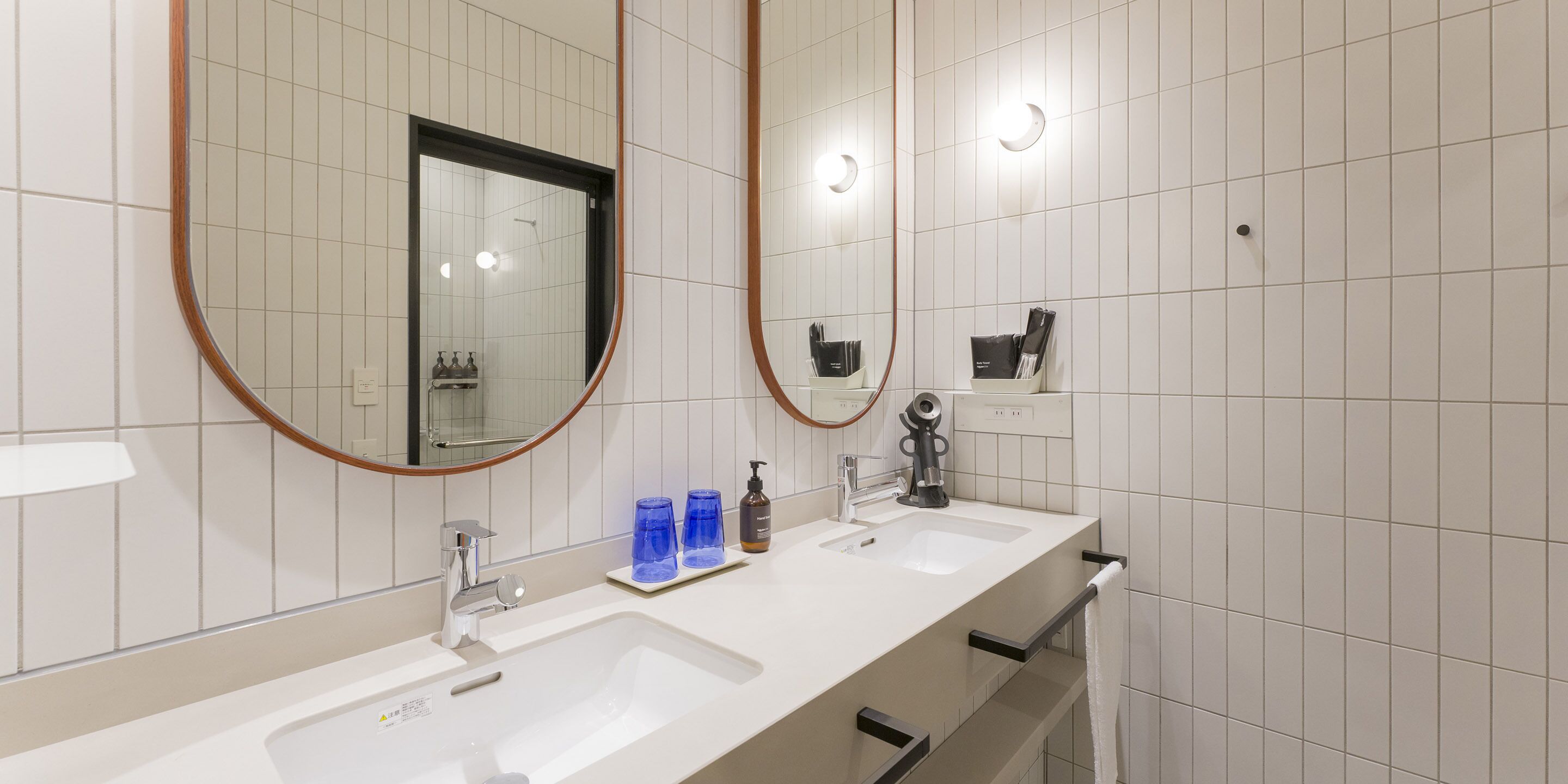 A modern bathroom with two sinks, a large mirror, and a towel rack.
