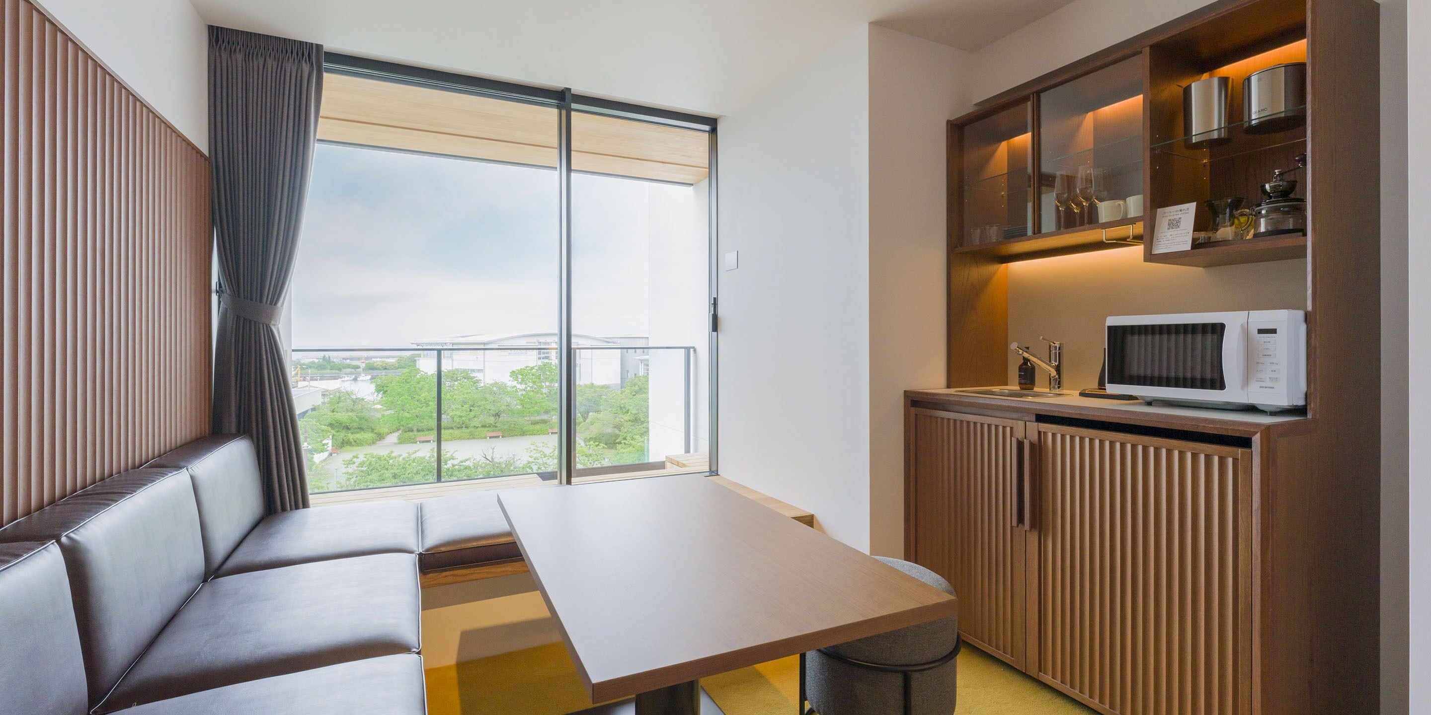 A modern room with a sofa, a dining table, and a kitchen area with a microwave.
