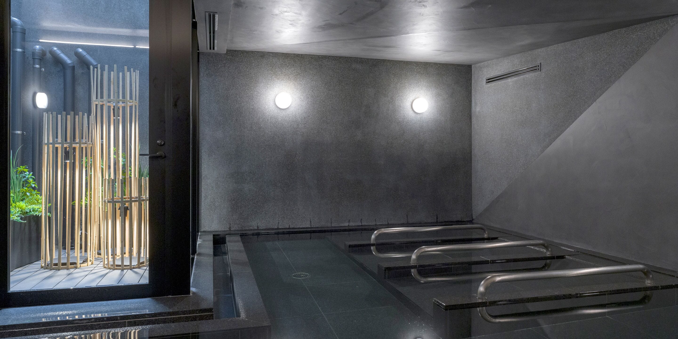 A modern spa room with a glass partition, a wooden fence outside, and a ceiling with recessed lighting.