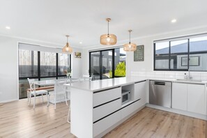 Una cocina moderna con armarios blancos, una isla central e iluminación colgante.