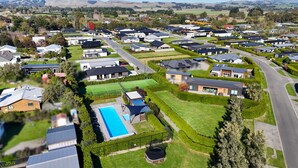 Ett bostadsområde med moderna hus, en swimmingpool och välskötta gräsmattor.