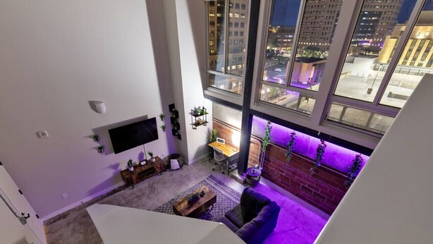 A high-rise apartment with a modern interior, a dining area, and a view of the cityscape through large windows. - Downtown Loft Skyline View 2BR (Des Moines)