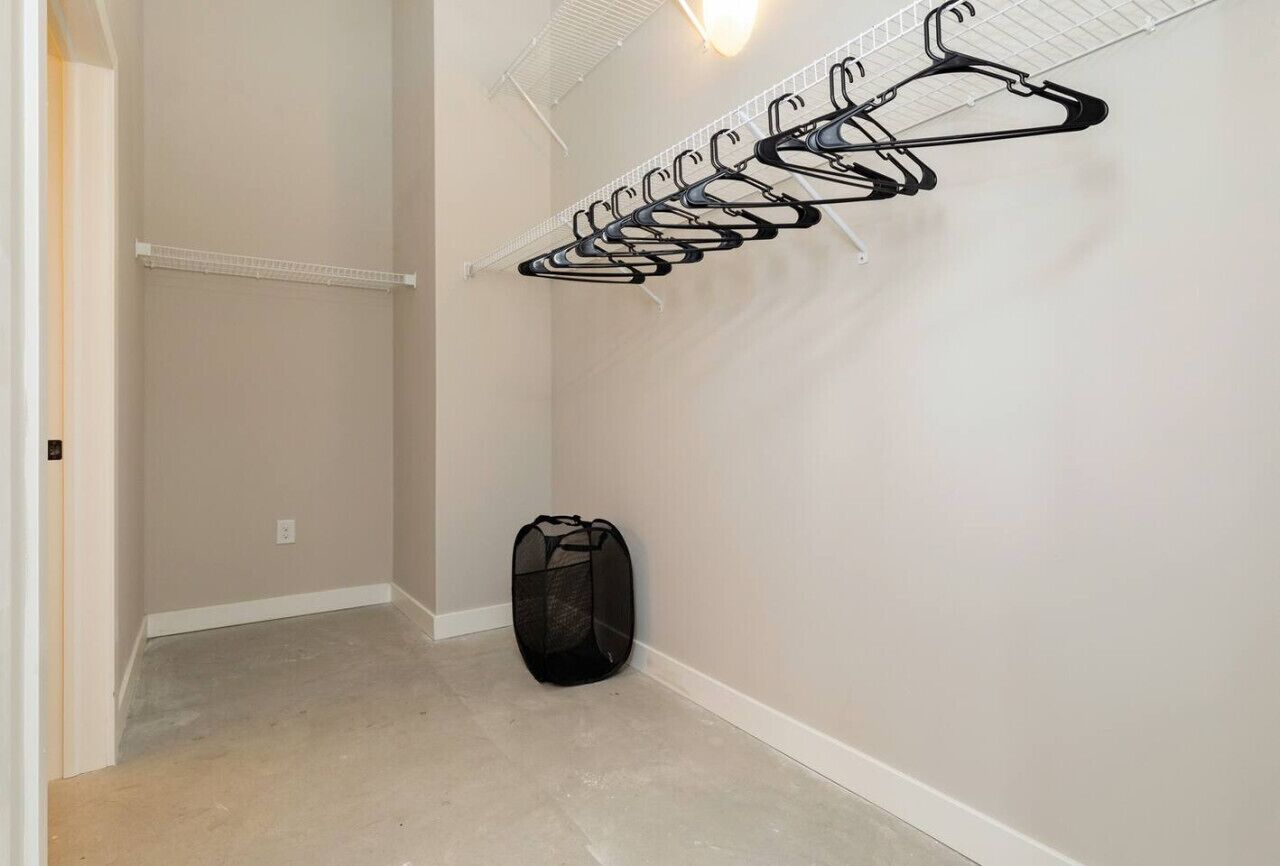 A hallway with a wall-mounted drying rack and a black mesh bag.