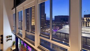 A view from a high-rise hotel room with large windows overlooking a cityscape at dusk. - Downtown Loft Skyline View 2BR (Des Moines)