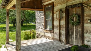 Una cabaña rústica con un porche de madera, un cartel de bienvenida y un adorno en la puerta.
