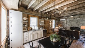 Una cocina rústica con armarios blancos, una mesa de comedor con sillas y una chimenea.