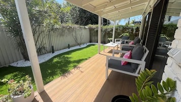 Relax in a serene outdoor space with a comfortable patio, complete with a wooden deck, two chairs, and a small table.