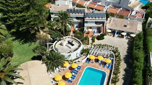 An aerial view of a resort with a swimming pool, sun loungers, and a circular garden area. - Charming Studio with Pool in Praia da Luz (Luz)