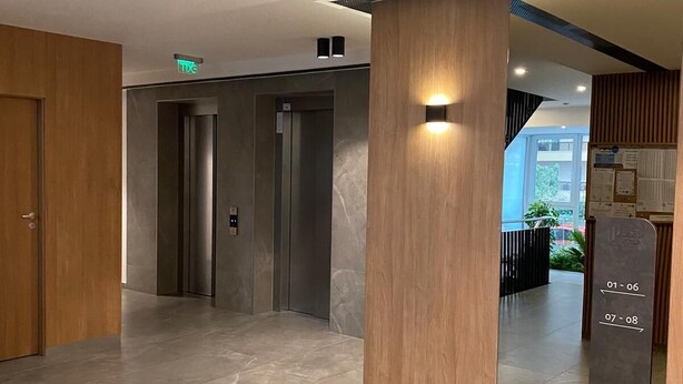 A modern hotel lobby with a marble floor, wooden paneling, and an elevator. - Charming 1-Bed Apartment in Brasov (Brasov)