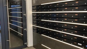 A modern storage room with metal lockers labeled with numbers, a glass door, and a sign indicating 'Carpatilor 93, Bloc 3'. - Charming 1-Bed Apartment in Brasov (Brasov)
