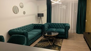 A modern living room with a sectional sofa, a glass coffee table, and a floor lamp. - Charming 1-Bed Apartment in Brasov (Brasov)
