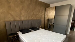 A modern bedroom with a large bed, a small side table, and a headboard. - Charming 1-Bed Apartment in Brasov (Brasov)