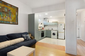 A modern apartment with a living area, kitchen, and laundry facilities.