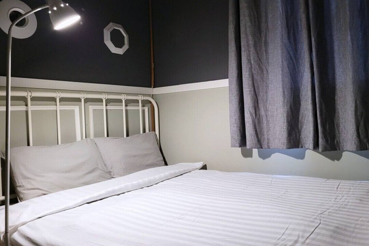 A bed with white bedding, a white headboard, and a bedside lamp.