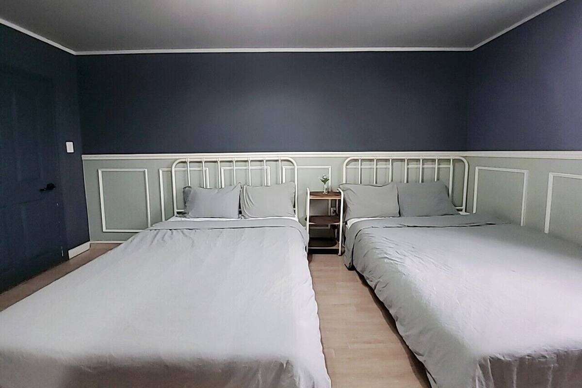 A room with two single beds, a nightstand, and a small table with a vase.