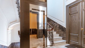 A grand entrance with a marble staircase, a glass door, and a large wooden door. - Nana Inn palazzo nana' (Napoli)