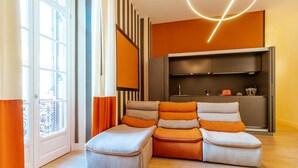 A modern living room with a sectional sofa, a built-in entertainment unit, and a large window with curtains. - Nana Inn palazzo nana' (Napoli)