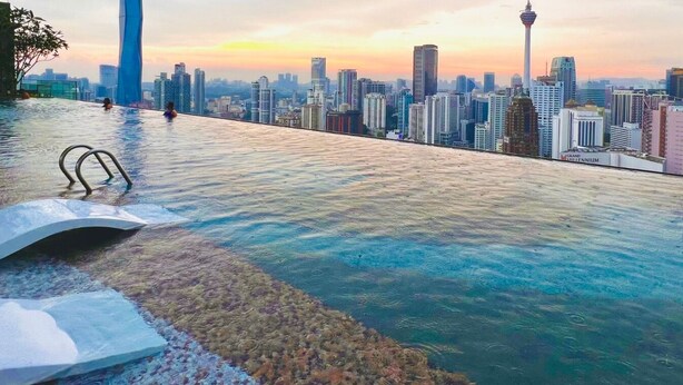 An infinity pool with a city skyline view at sunset. - The Axon Bukit Bintang by SMOVF BNB (Kuala Lumpur)