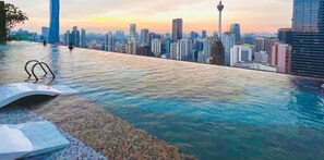 An infinity pool with a city skyline view at sunset. - The Axon Bukit Bintang by SMOVF BNB (Kuala Lumpur)
