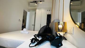 Una habitación de hotel con una cama bien hecha, un secador de pelo y una lámpara en la mesita de noche.