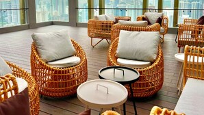 A high-rise hotel room with wicker furniture, large windows, and a city view. - The Axon Bukit Bintang by SMOVF BNB (Kuala Lumpur)