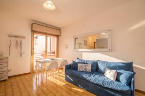 Ein Zimmer mit einem blauen Sofa, einem weißen Schreibtisch und einem Stuhl.