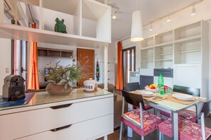 A modern kitchen with white cabinetry, a dining table with chairs, and a coffee station.
