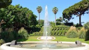 A fountain surrounded by a circular stone border, with palm trees and a well-maintained lawn in the background. - Vicerè Apartment With AC and Wi-Fi, Catania, Italy (Catania)
