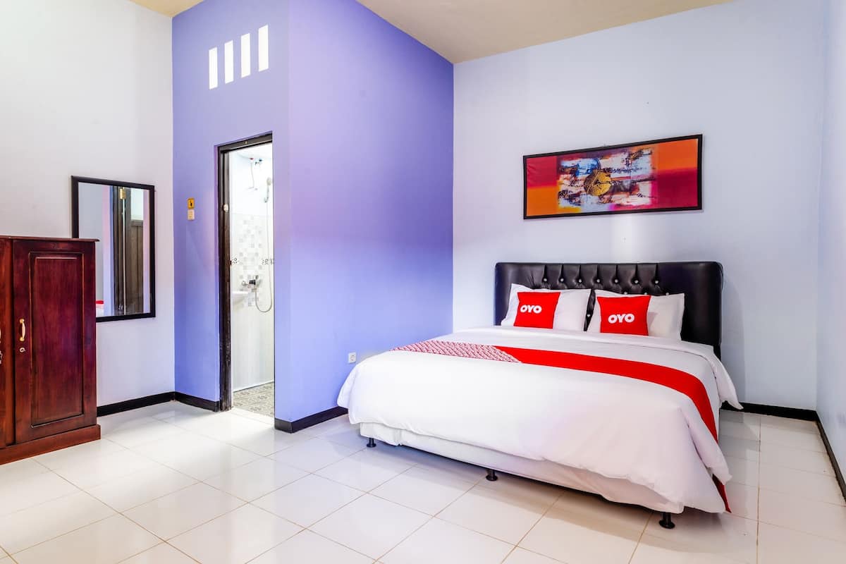 Ein Schlafzimmer mit Bett, Schrank, Tür und einem Bild an der Wand.
