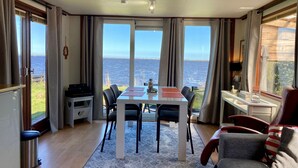 Una habitación con una mesa de comedor, sillas, un sofá, un televisor y vistas al mar.