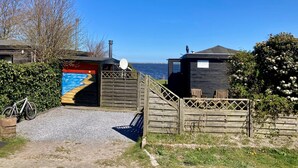 Una construcción de madera con un mural colorido, una antena parabólica y vista al mar.