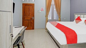 A hotel room with a bed, a desk, and a door. - Hotel O Gm Guest House (Wonogiri)