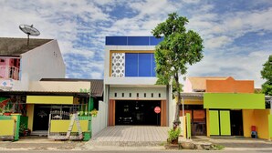 A modern building with a large entrance, a satellite dish, and a tree in front. - Hotel O Gm Guest House (Wonogiri)