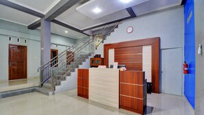 A reception area with a wooden reception desk, a staircase, and a fire extinguisher on the wall. - Hotel O Gm Guest House (Wonogiri)