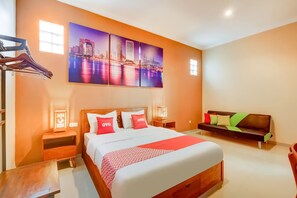 A hotel room with a large bed, a wooden nightstand, a bench, and a wall-mounted TV.