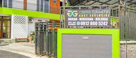 Una entrada cerrada a un edificio con un cartel que anuncia un hotel llamado 'Griya Gayatri' y un número de contacto.