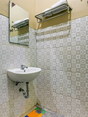 A bathroom with a white sink, a mirror, and patterned tiles.