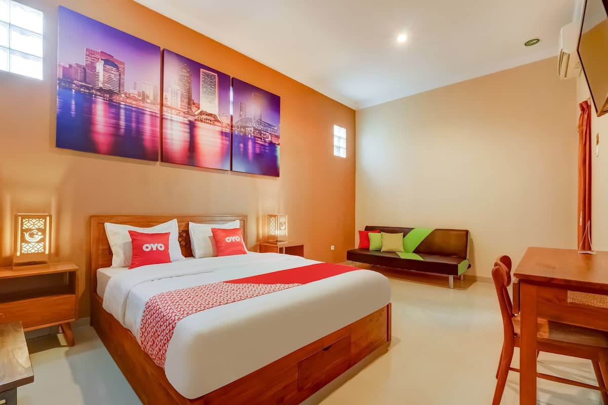 Habitación de hotel con una cama grande, un escritorio, un sofá y un cuadro de un paisaje urbano en la pared.