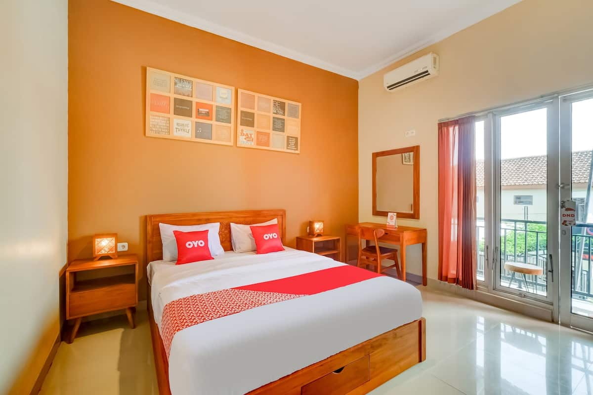 Habitación de hotel con una cama grande, cabecero de madera, dos mesitas de noche con lámparas, un escritorio con silla, un ventanal con cortinas y una pared con citas inspiradoras enmarcadas.