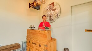 A wooden desk with drawers, a bench, and a wall with a circular artwork.