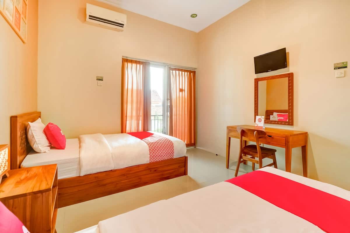 Habitación de hotel con cama, escritorio, silla, televisor y aire acondicionado.