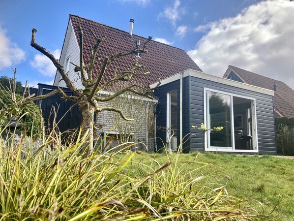 A modern house with a sloped roof, a stone foundation, and a large sliding glass door.