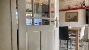 Un comedor con una mesa y sillas, un cuadro en la pared y vistas a través de un ventanal.
