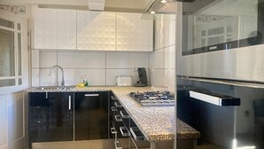 Una cocina moderna con un refrigerador de acero inoxidable, un horno empotrado, una estufa a gas y un lavamanos.