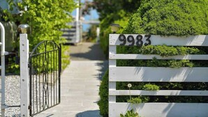 A gated entrance with a white picket fence and a sign displaying the number 9983. - Gulf Island View Suite (Chemainus)