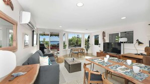 A modern living room with a sofa, dining table, and TV. - Gulf Island View Suite (Chemainus)