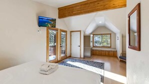 Een slaapkamer met een bed, een televisie, een balkon en uitzicht op de omgeving.
