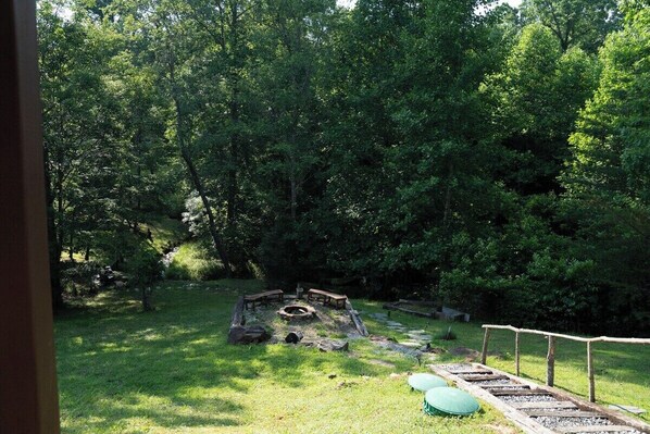 Un espace extérieur aménagé, de façon naturelle, avec un foyer, des sièges et un chemin en pierre.