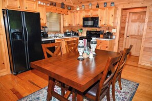 A wooden kitchen with a refrigerator, microwave, stove, and cabinets.