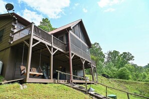 A two-story wooden house with a porch and swing chairs.